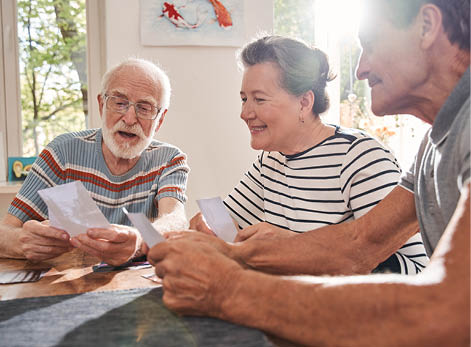 My memories. Three retirement people sitting at the table at the living room and watching at the old photos while spending their time at the nurse house